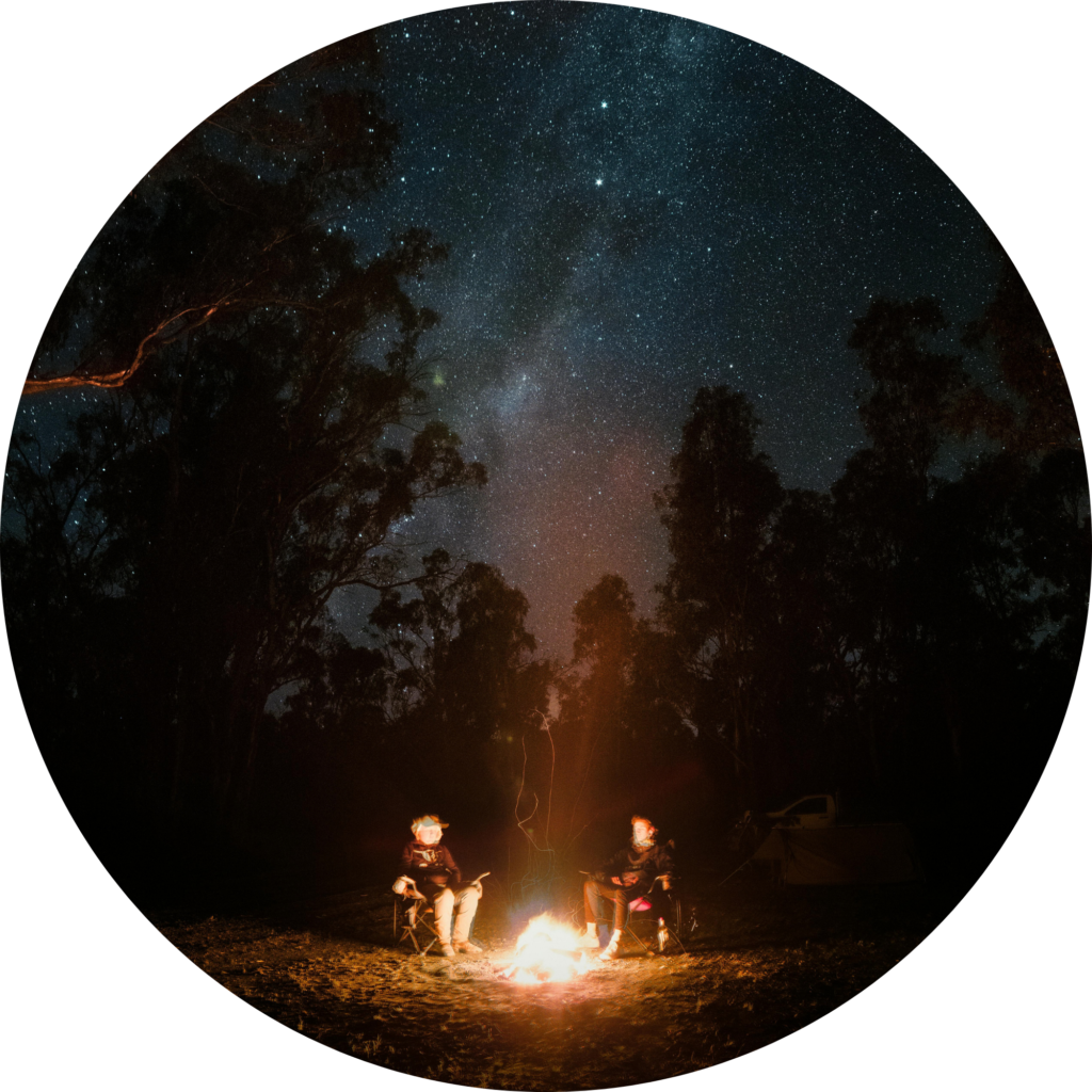 Two people sitting at a campfire under the stars